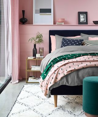 pink bedroom with a gold coffee table and grey bedding