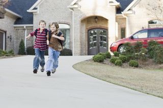 Two boys happily running in a driveway.