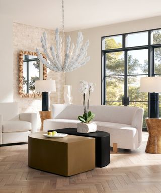 White living room with large statement pendant lamp, large black table lamps and parquet floors