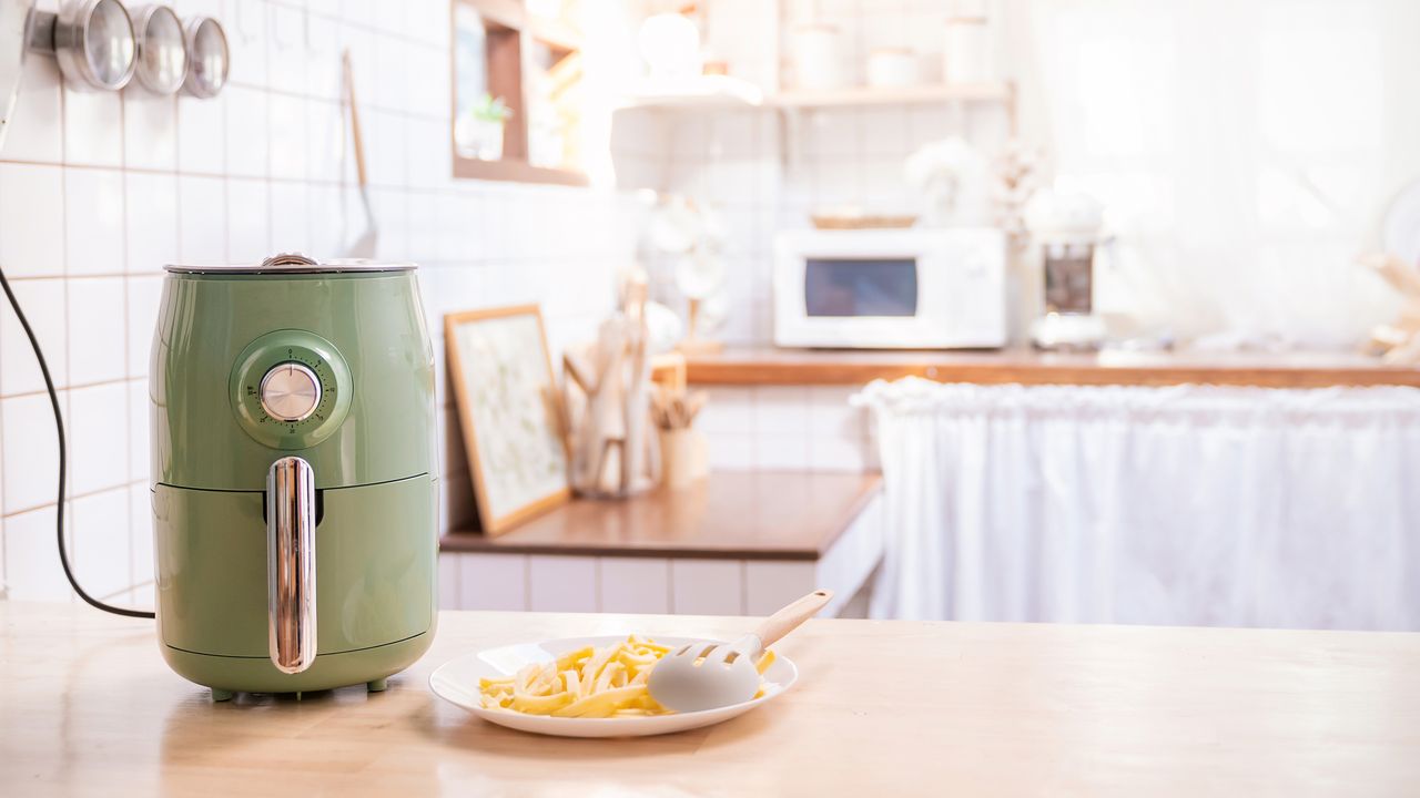 Air fryer machine cooking potato fries in kitchen