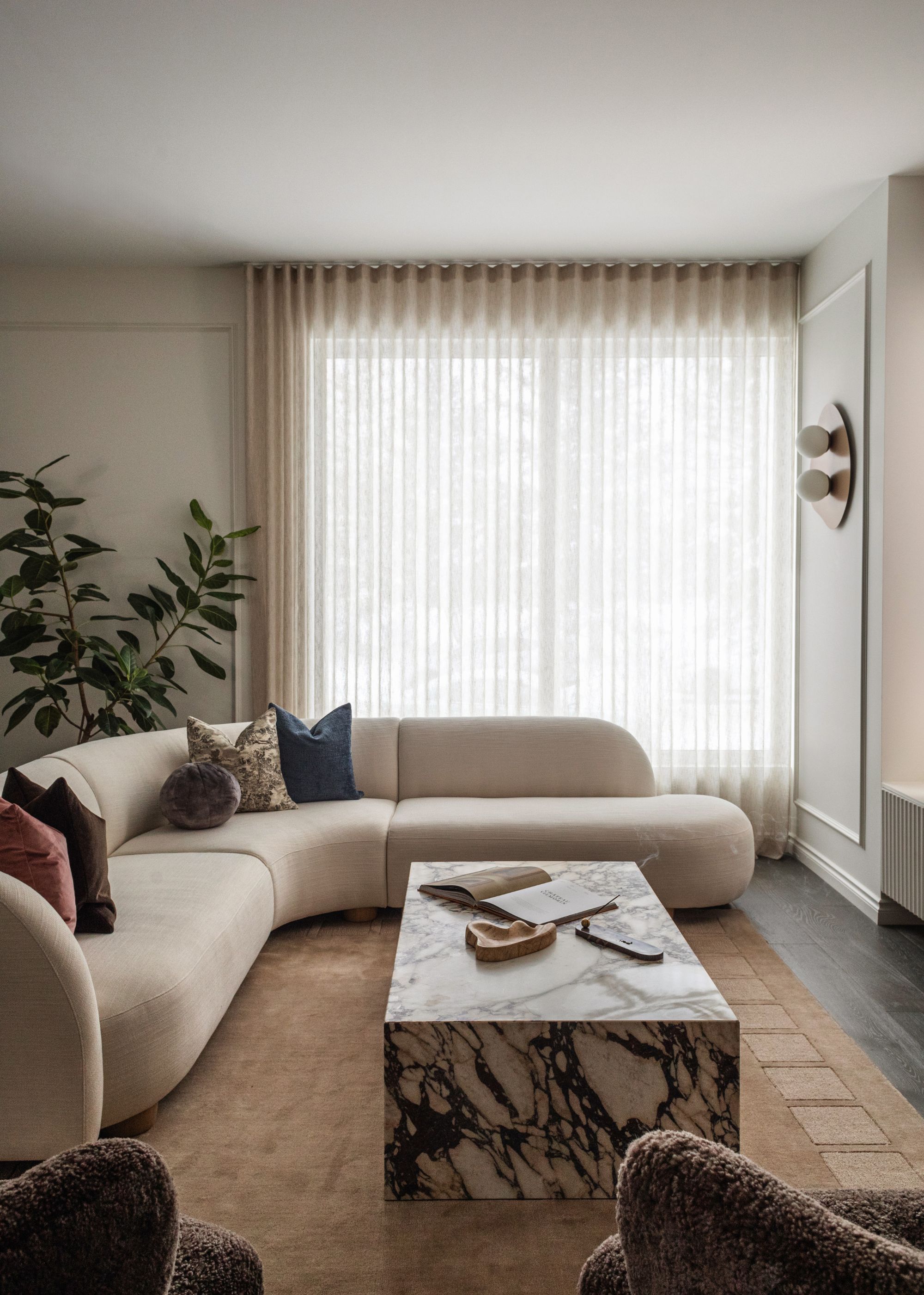 A living room with a marble coffee table and a curved sofa