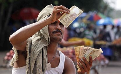 A street vender checks the authenticity of a rupee.