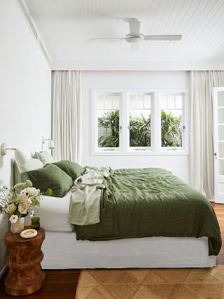 modern bedroom with green bed linen, timber side table and jute rug