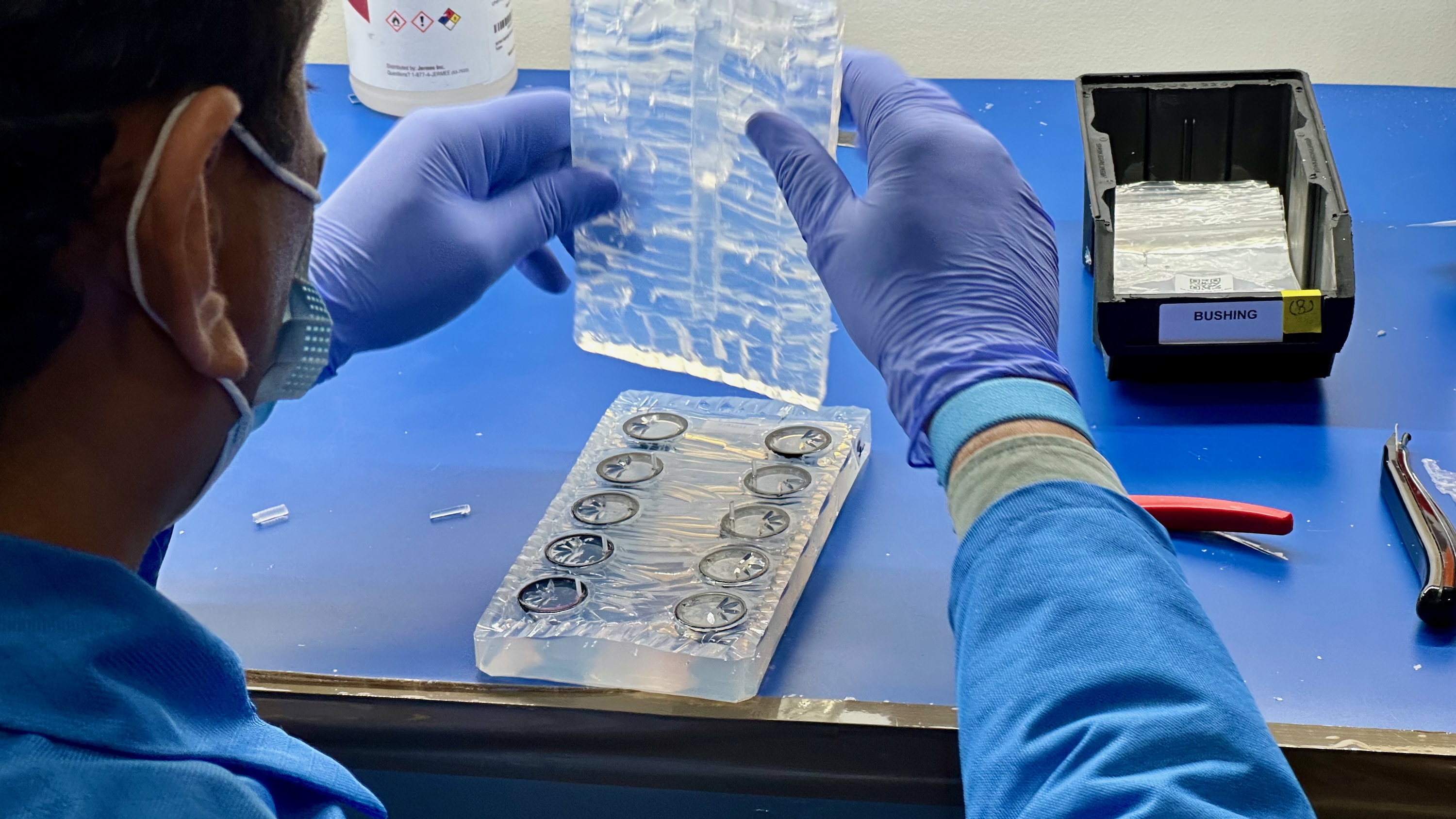 An Ultrahuman factory worker removing the top of a silicone mold with twelve Ring Air units that had resin inserted.