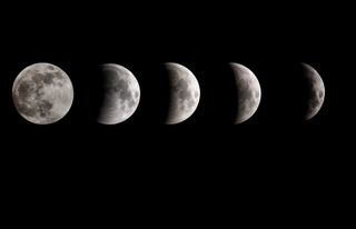 A composite image shows the Earth's shadow beginning to cross the surface of the moon during the partial eclipse phase of the lunar eclipse on January 21, 2019 in Manchester, United Kingdom