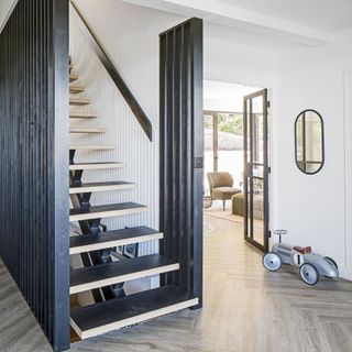 Large hallway with open treat staircase and graphite grey painted modern panelling either side of the stairs