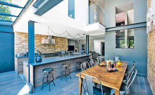 Open-plan kitchen-diner in contemporary self build with high ceilings and exposed brick walls