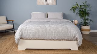 The Saatva Classic mattress, dressed in pale gray bedding, in a decorated room in our Sleep Lab.