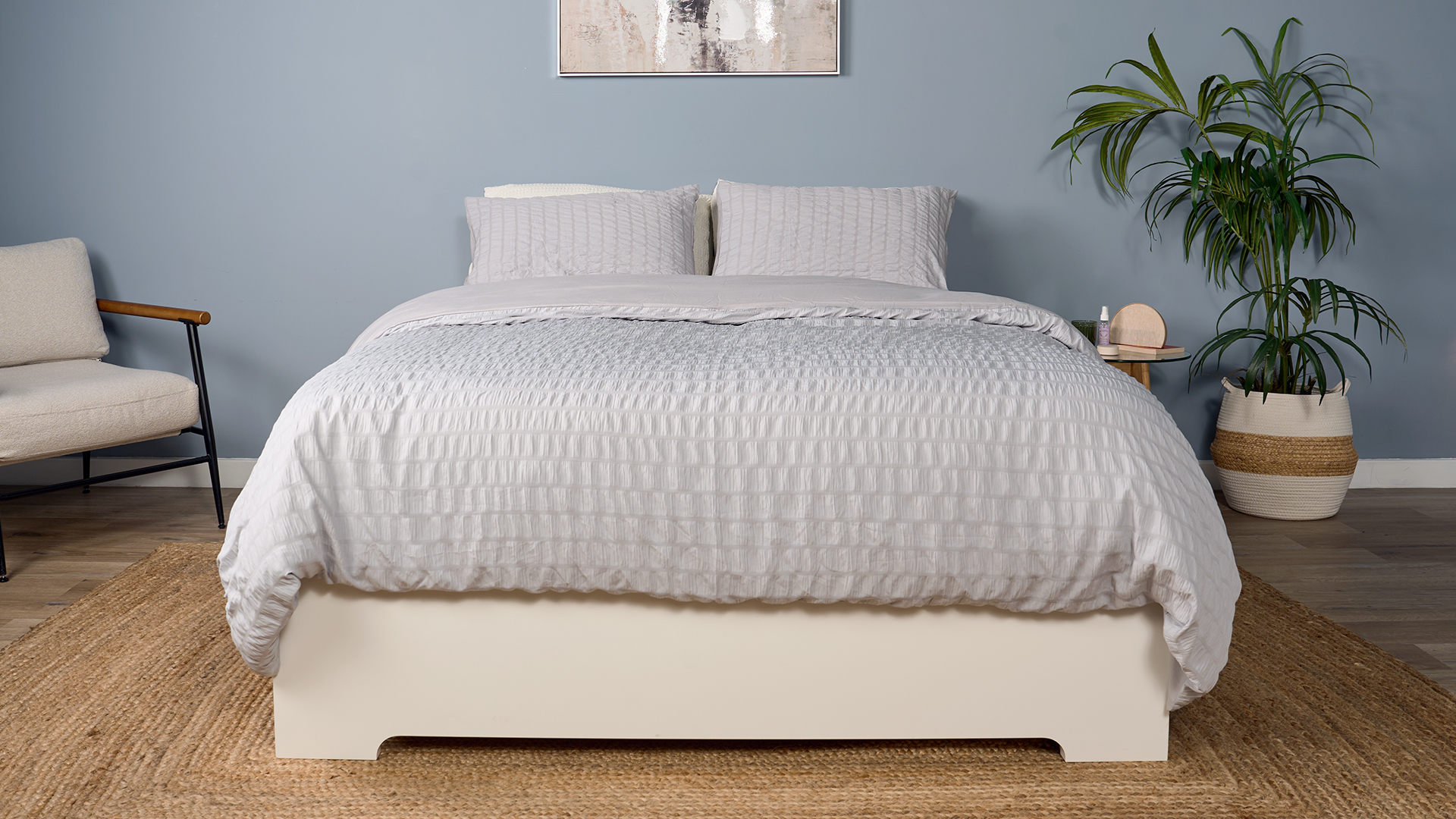 The Saatva Classic mattress, dressed in pale gray bedding, in a decorated room in our Sleep Lab.