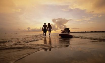 A couple walks off into the sunset on a Florida beach.