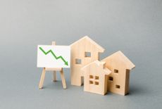 Wooden houses next to an easel with a green downward arrow on it