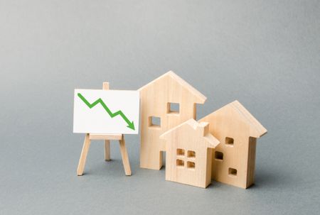 Wooden houses next to an easel with a green downward arrow on it