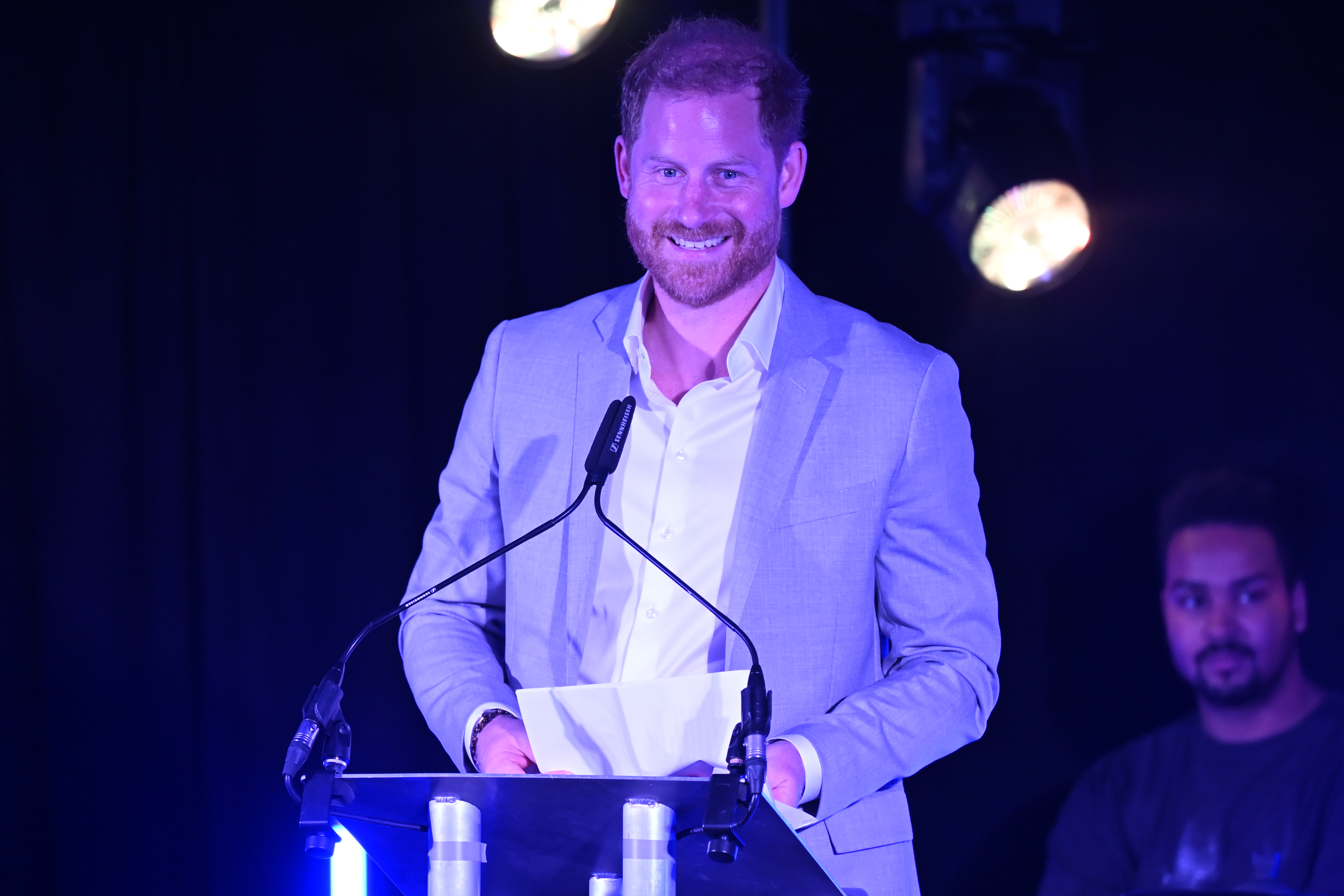 Prince harry giving a speech and smiling at a podium