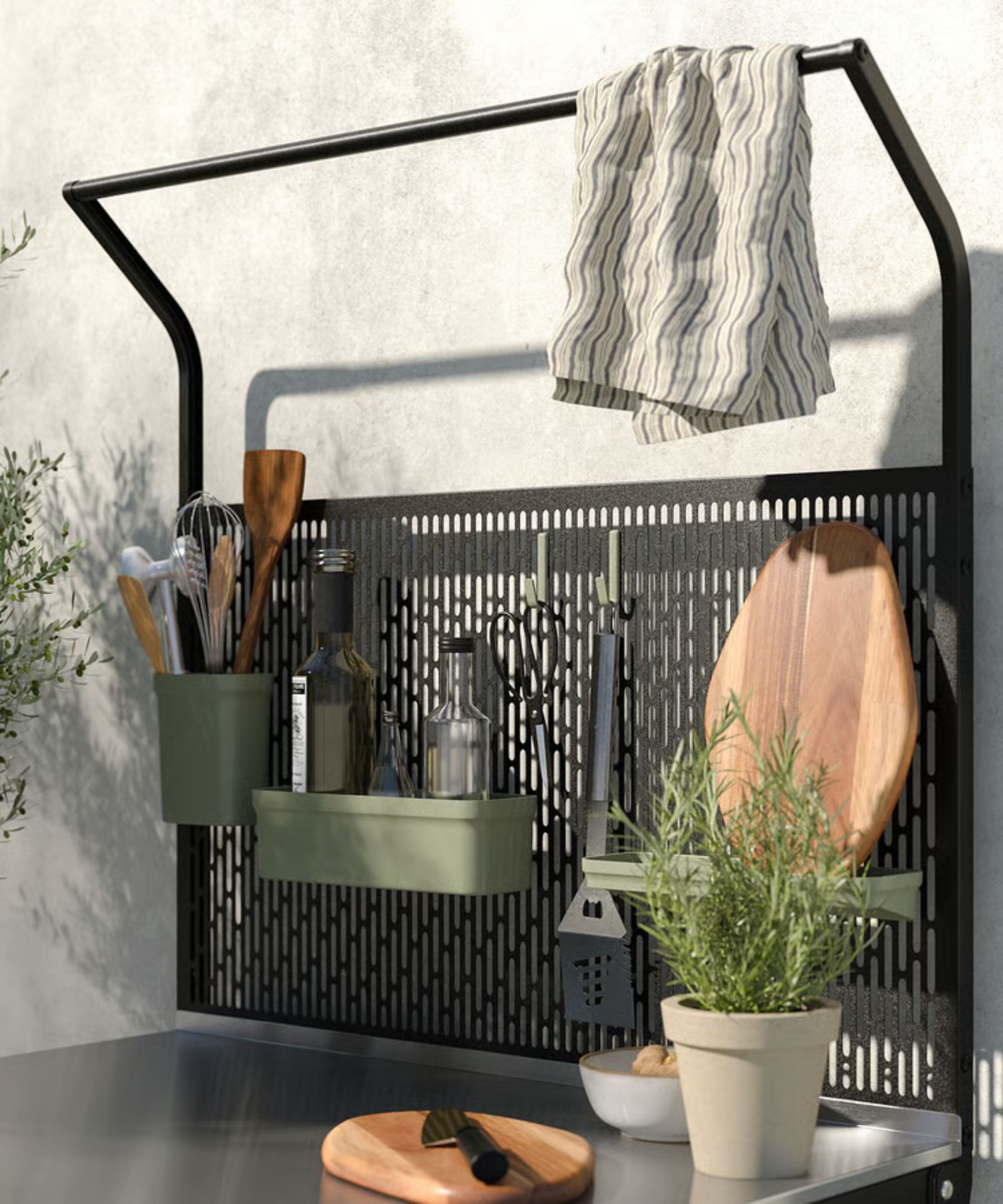 Outdoor kitchen with steel work surface, kitchen utensils, wood chopping board and rosemary potted plant