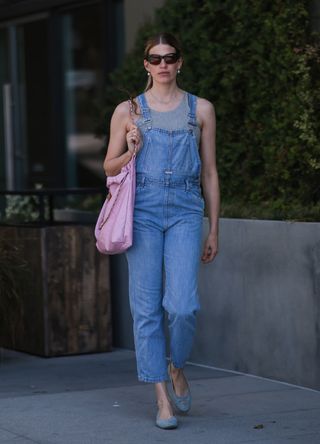 Veronika Heilbrunner seen wearing a grey top from Zara, blue denim overalls from Calvin Klein, a light pink Chanel 22 shopper bag and blue denim ballerinas from Chanel