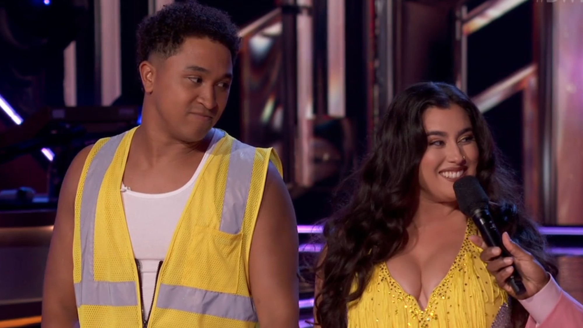 Brandon Armstrong wearing a yellow construction vest and Lauren Jauregui wearing a yellow dress on DWTS. 