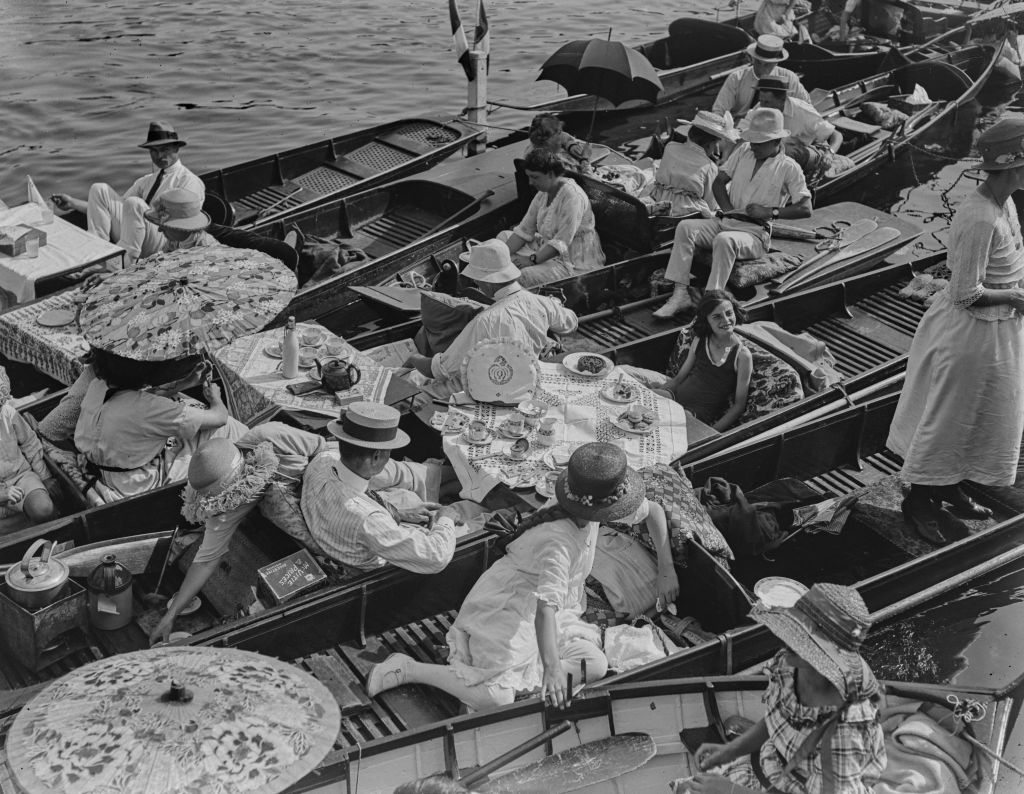 July 1921:  Revellers enjoy a meal aboard their punts during the Kingston Regatta at Kingston-Upon-Thames, Surrey.  