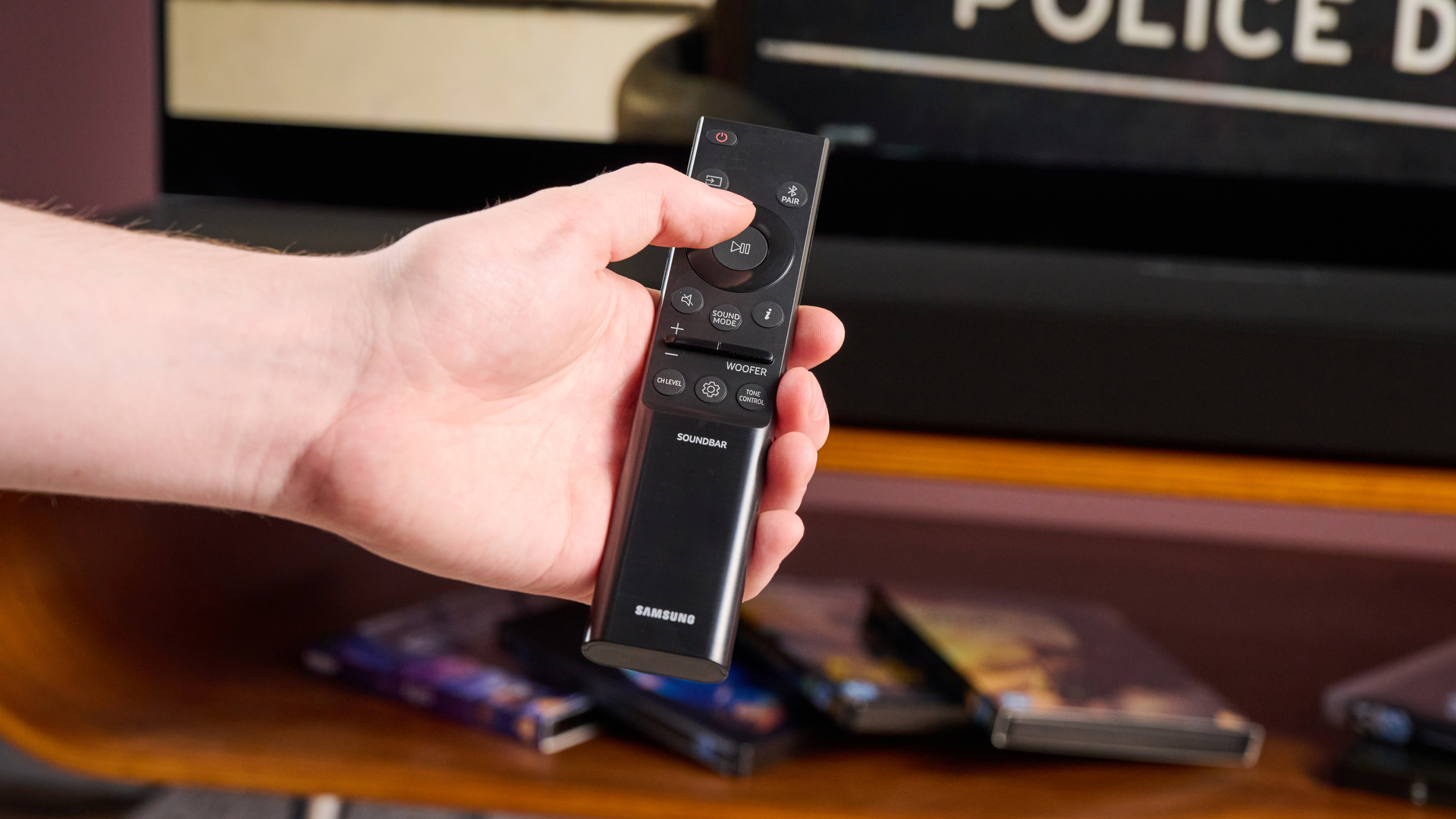 Person pressing button on the remote control of the Samsung HW-Q800F