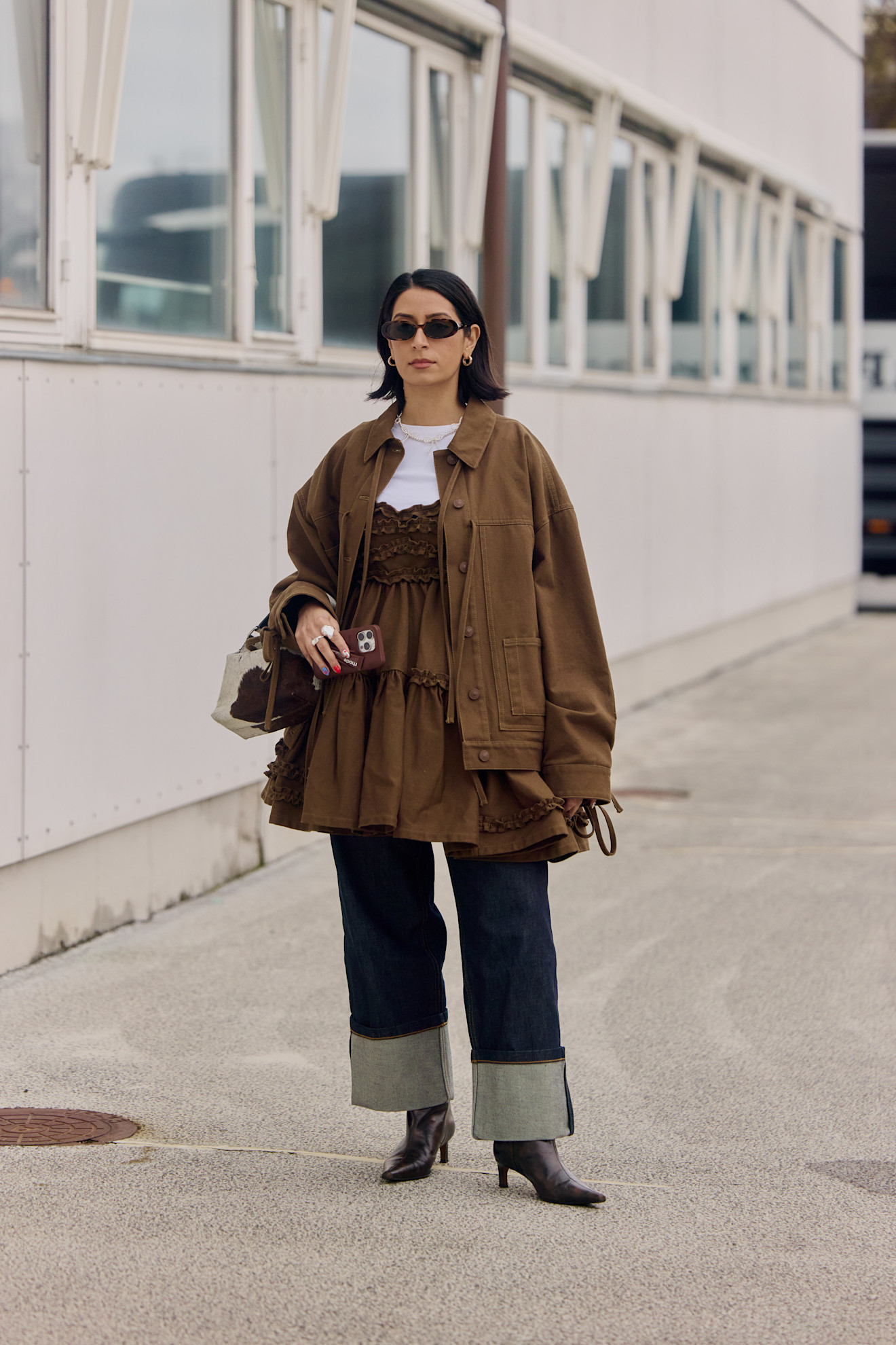 woman wearing brown dress, jeans, and brown jacket