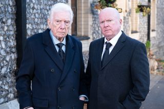 Stevie Mitchell and Phil Mitchell wearing black suits outside a church.