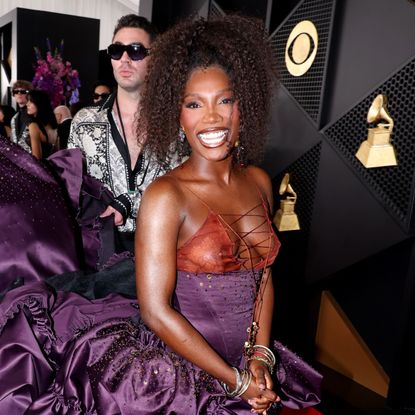 a black woman with brown hair poses on the grammys red carpet