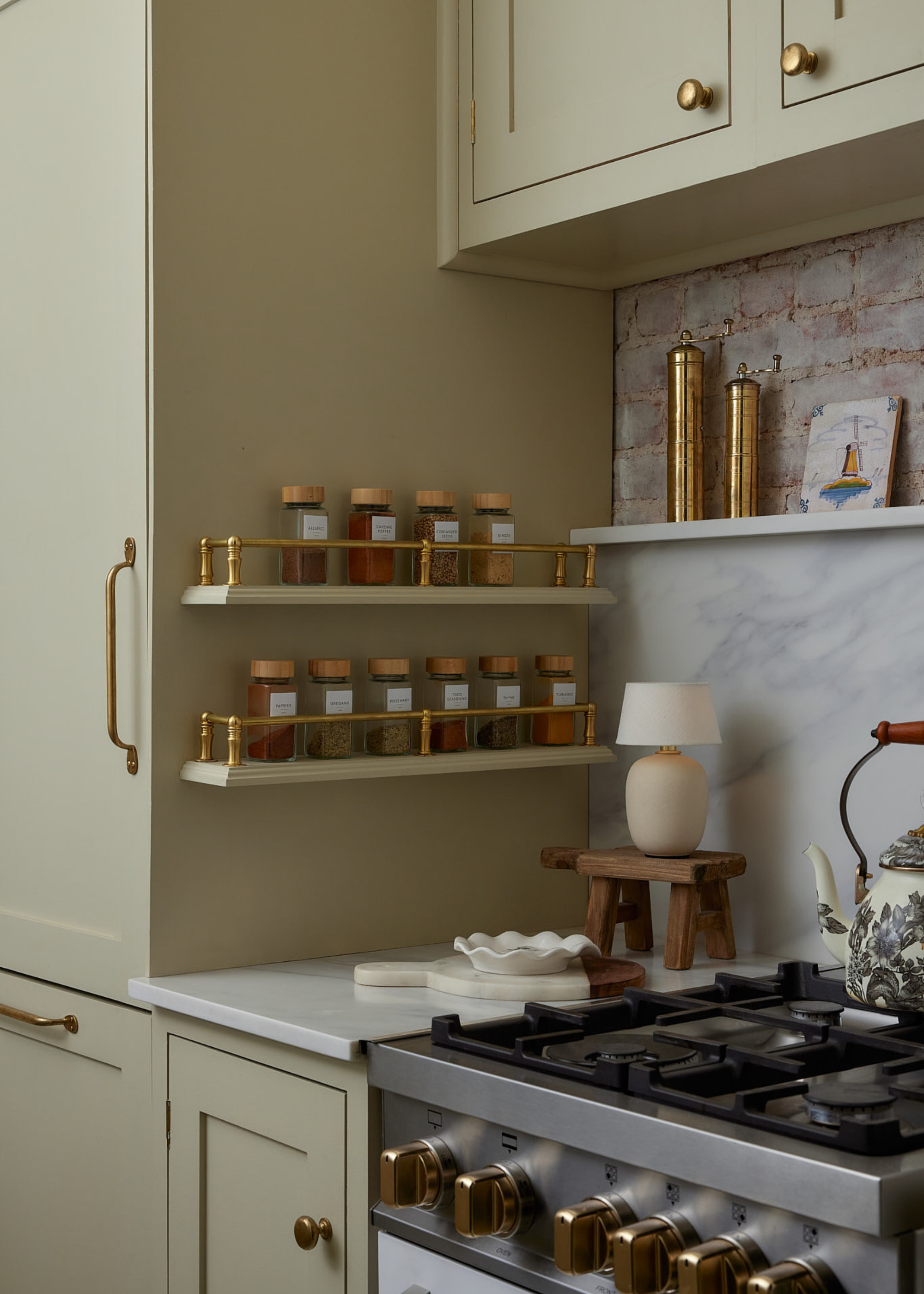 close up of a tiny kitchen with soft, pale green cabinetry and gold hardware features