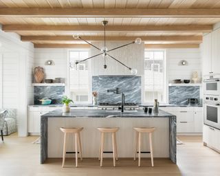 A white kitchen with green marble backsplash and island countertop, illustrating white kitchen backsplash ideas.