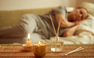 Woman asleep with scented candles and diffuser in foreground