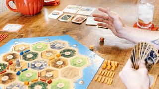 Someone rolls dice at the table while playing Catan