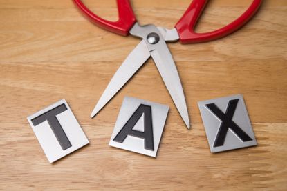 the word tax on metal tiles with a pair of scissors above it