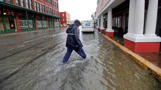 A postman walks through streets flooded by the tropical storm Imelda, as he delivers mail in Galveston, Texas.