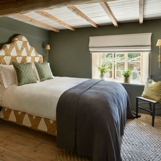 dark green painted cottage bedroom with upholstered, shaped headboard