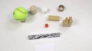 Still from STEMscopes video: STEMscopes Math - Two- and Three-Dimensional Figures, showing baseball and small wooden objects.