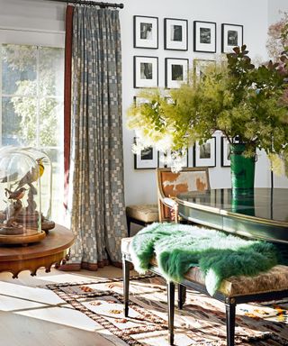 dining room with gray patterned curtains, gallery wall, black oval chair, cowhide bench and armchair, green fleece and patterned rug