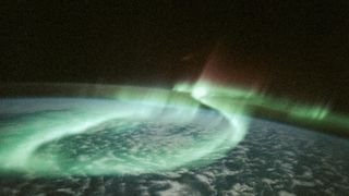 a photograph of a green-blue aurora australis from the Space Shuttle Discovery
