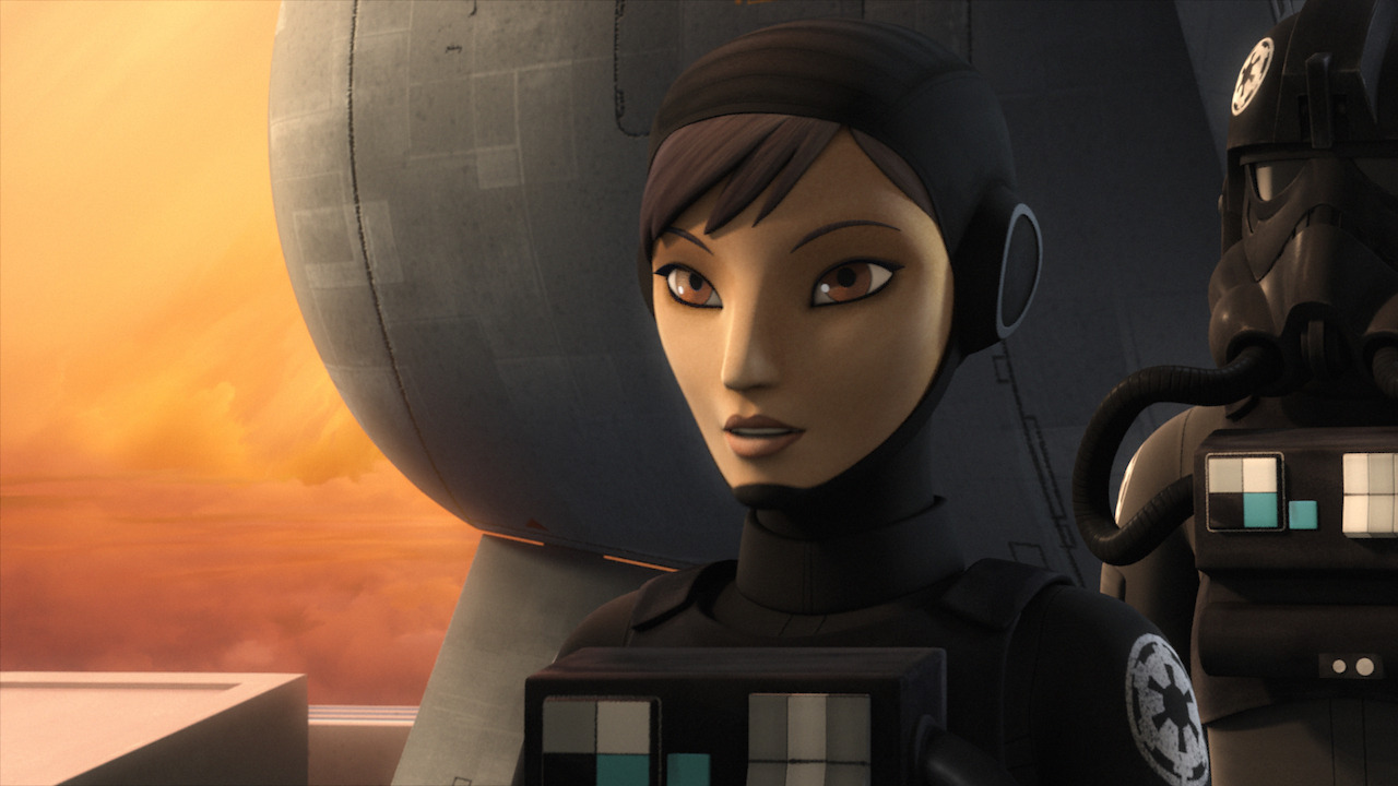 Still from the Star Wars T.V. Show Star Wars Rebels. Here we see Sabine Wren with short, pixie dark hairstyle and light brown eyes. She is wearing a black suit with a logo on the shoulder showing that she belongs to the Galactic Empire. The logo is a black cog with six spokes on a white cog with six spokes.