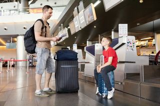 Father and son waiting at airport check in with their luggage