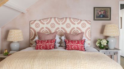 An example of bed ideas showing a bed with a pink and white upholstered headboard in front of a pink wall