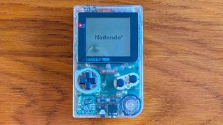 Transparent Game Boy Color on woodgrain table.
