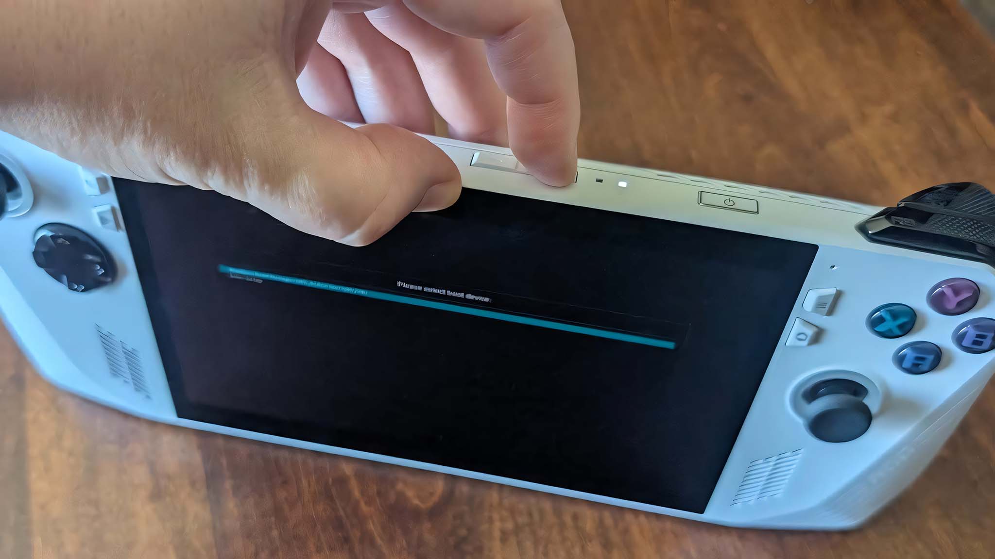 A finger holding down the volume up button on ROG Ally.