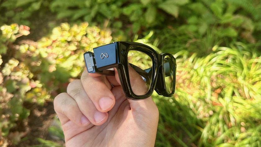 A close-up of the Meta Ray-Ban Display glasses held in hand from a side view showing the Meta logo and the thickness of the frames.