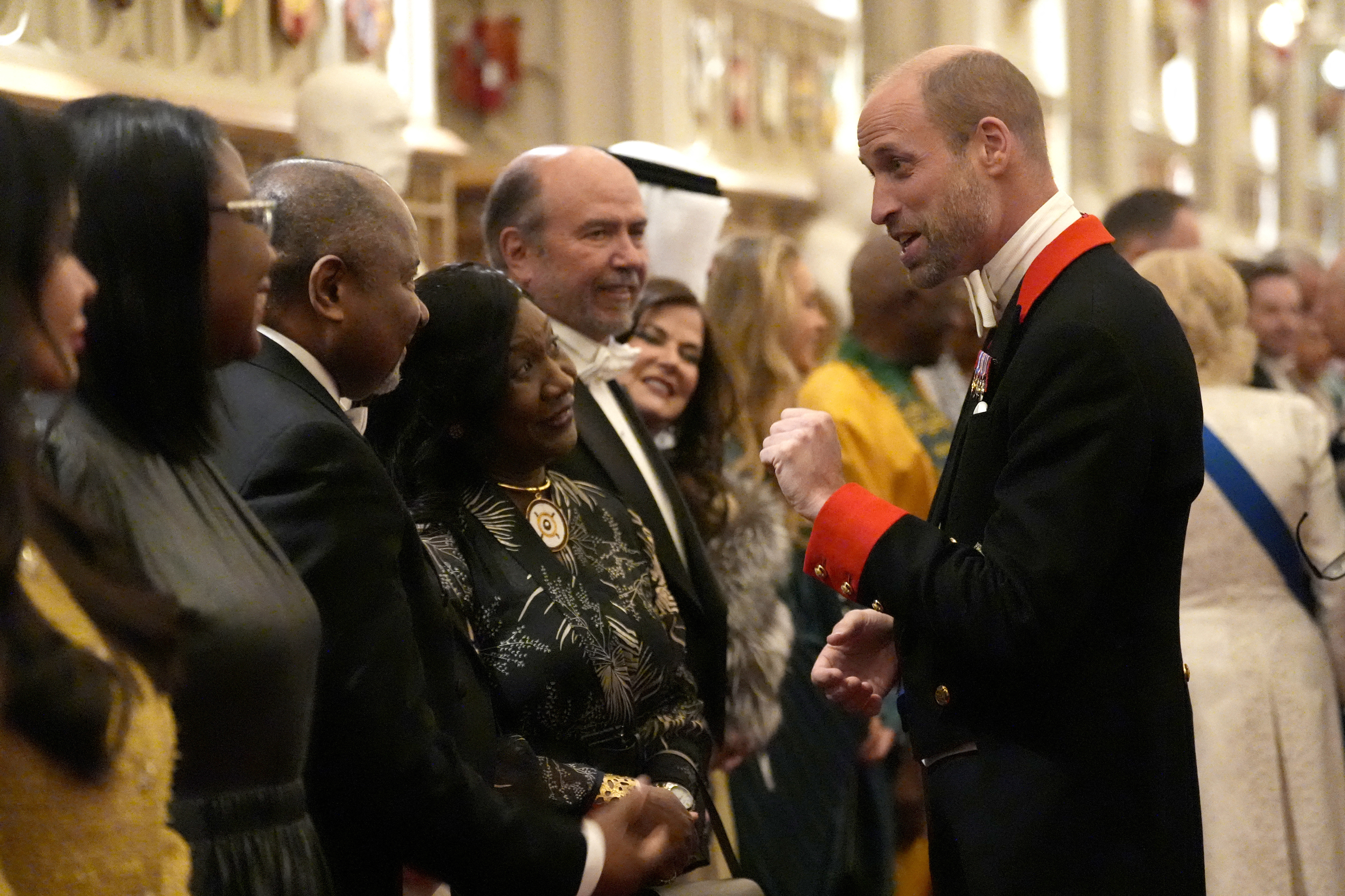 Prince William wearing a black uniform talking to a line of guests at a diplomatic reception