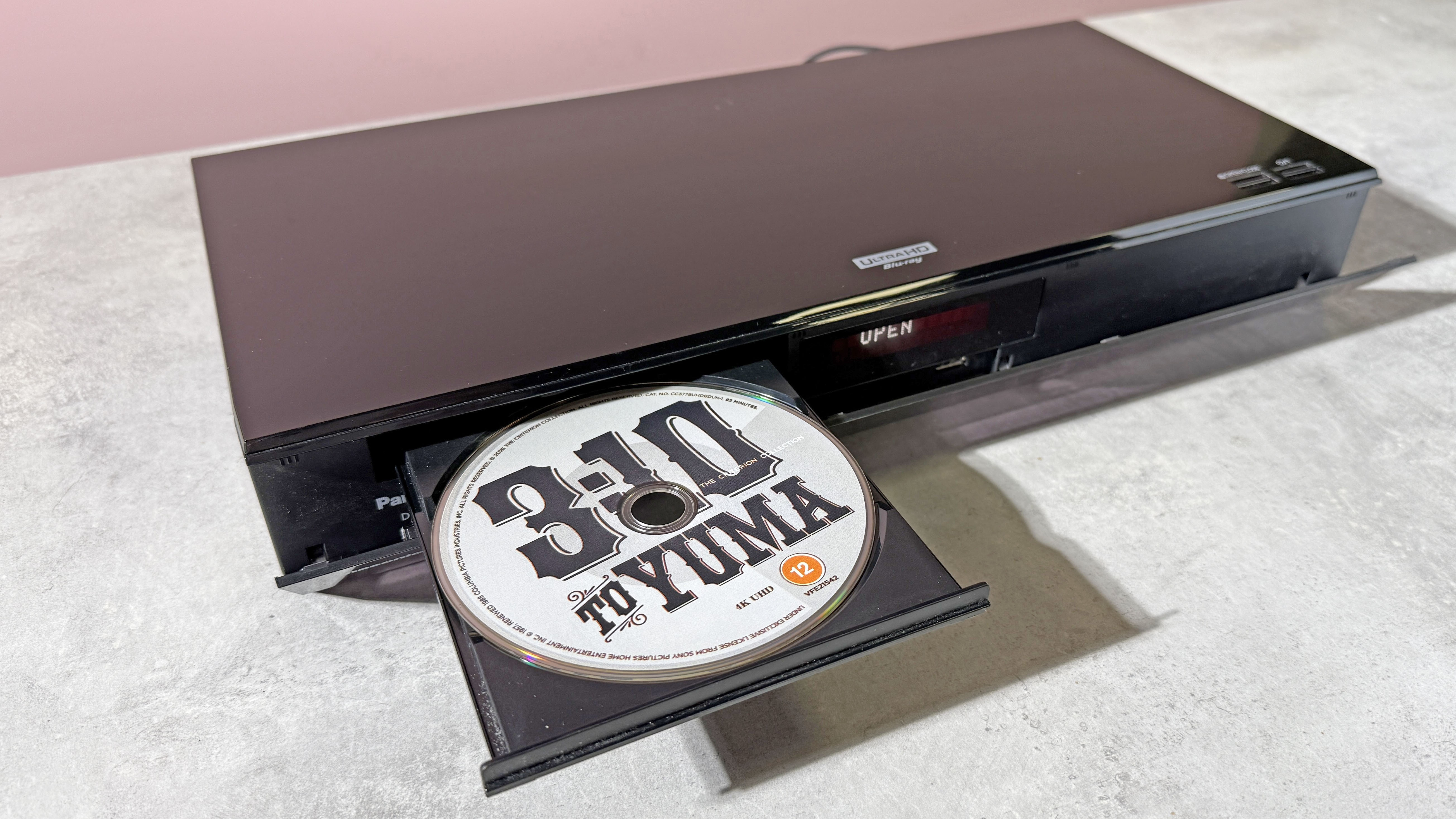 A Panasonic DP-UB820 4K Blu-ray player, with its disc tray open, and copy of 3:10 to Yuma on 4K Blu-ray disc in the tray