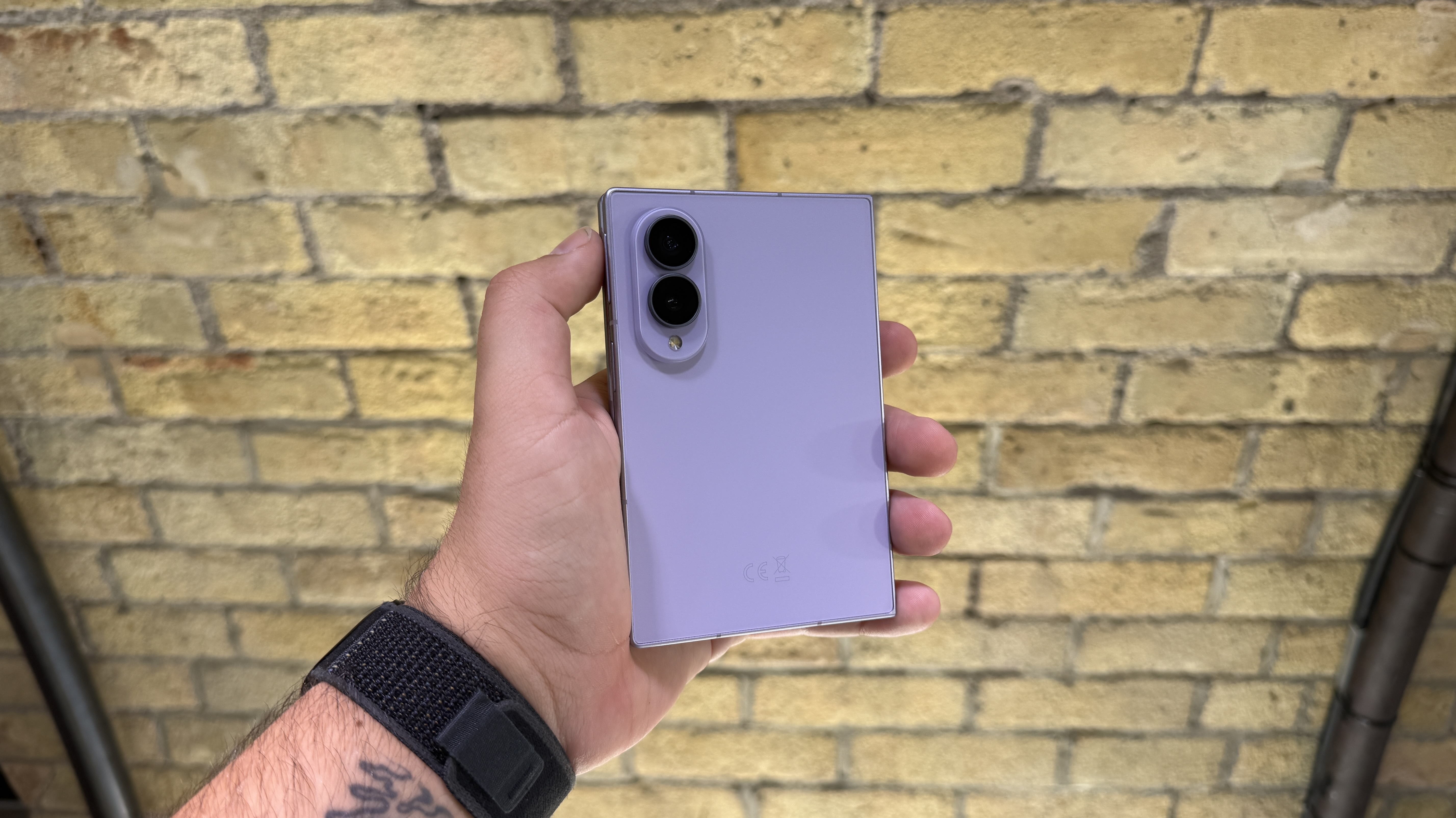 Samsung Galaxy Z Fold 8 and 8 Ultra in hand at a hands on event with a brick wall in the background