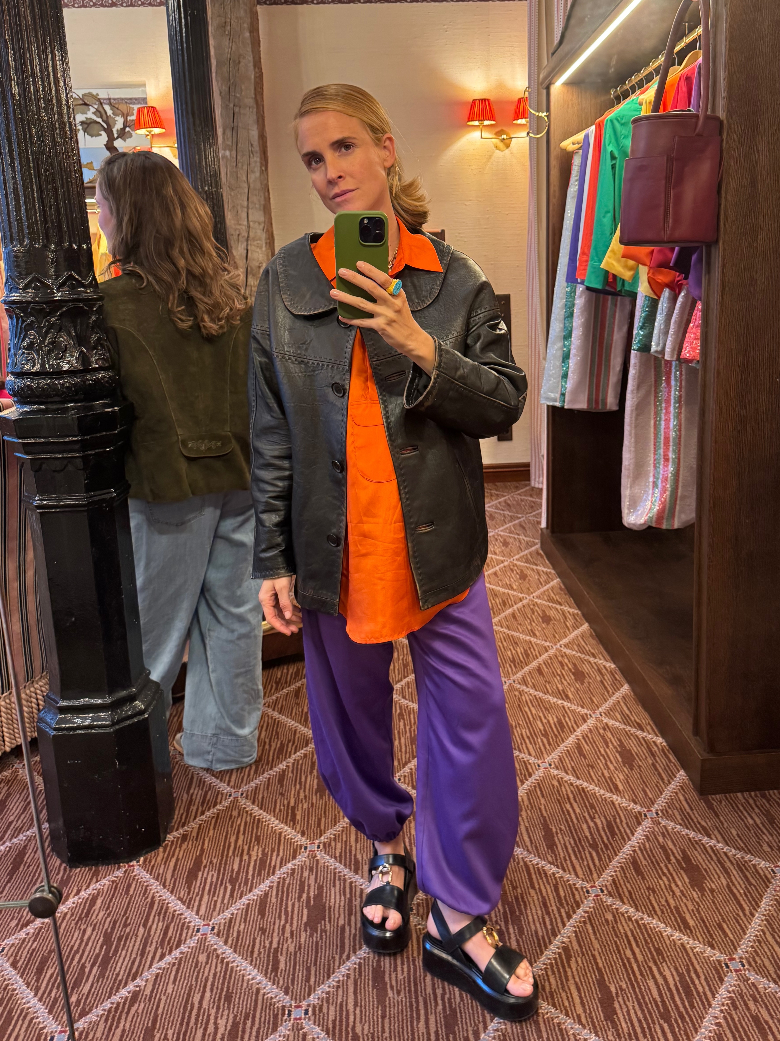 Blanca Miro wears a leather jacket, orange shirt and purple trousers.