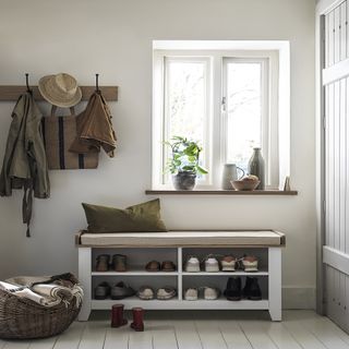 white entryway with closet, shoe store, white floorboards, peg rail