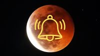 an almost full eclipsed moon with a majority of the surface appearing a rusty red hue and the lower left portion still bright white. there is a yellow notification bell graphic in the center.