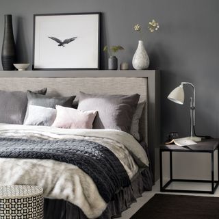 bedroom with grey wall grey bed with grey and white cushion