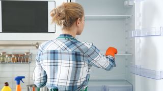 Woman cleaning empty fridge