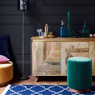 room with blue wall and wooden floor and penfold stool and sideboard